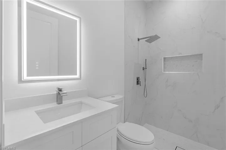 Bathroom with a tile shower, vanity, and toilet