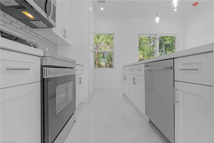Kitchen with appliances with stainless steel finishes, decorative backsplash, and white cabinetry