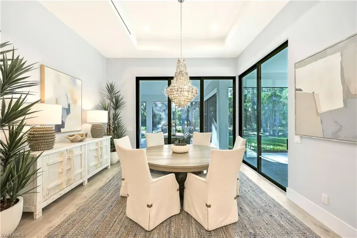 Dining space with hanging lights, a raised ceiling, and light wood-style flooring