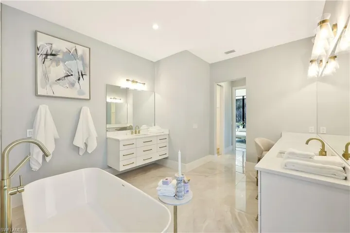 Full bath with two vanities, a soaking tub, and recessed lighting
