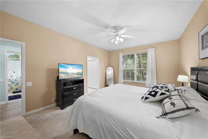 Bedroom with light colored carpet, a ceiling fan, and a closet