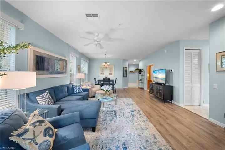 Living room with light wood-type flooring, ceiling fan, and hanging lights