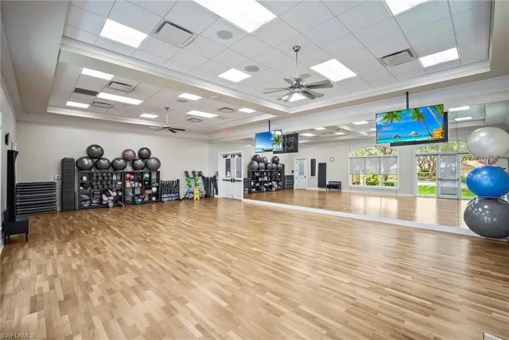 Gym featuring ceiling fan, a paneled ceiling, a raised ceiling, and crown molding