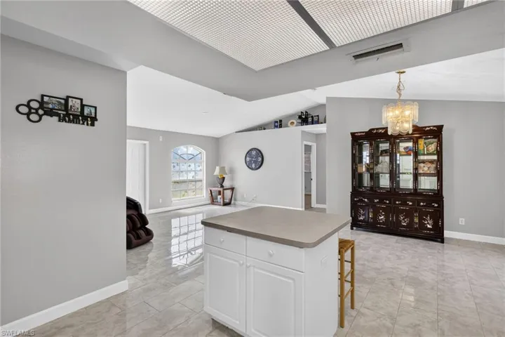 Kitchen with a breakfast bar, a kitchen island, vaulted ceiling, suspended lighting, and open floor plan