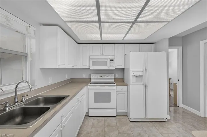 Kitchen with white appliances, white cabinets, and light countertops
