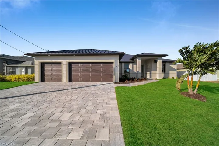Prairie-style house with decorative driveway, stucco siding, a garage, and a standing seam roof