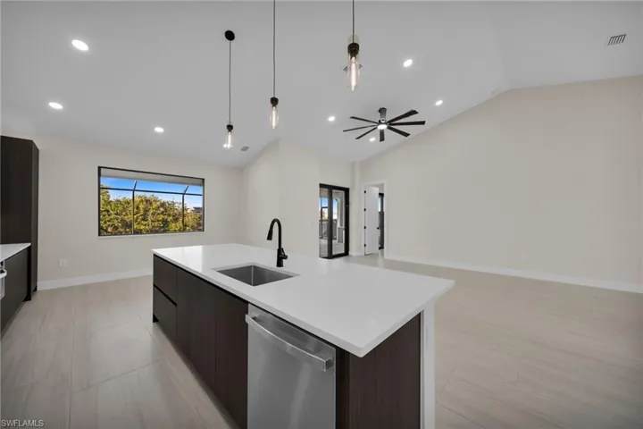 Kitchen featuring dark wood finish cabinetry, dishwasher, modern cabinets, open floor plan, and lofted ceiling