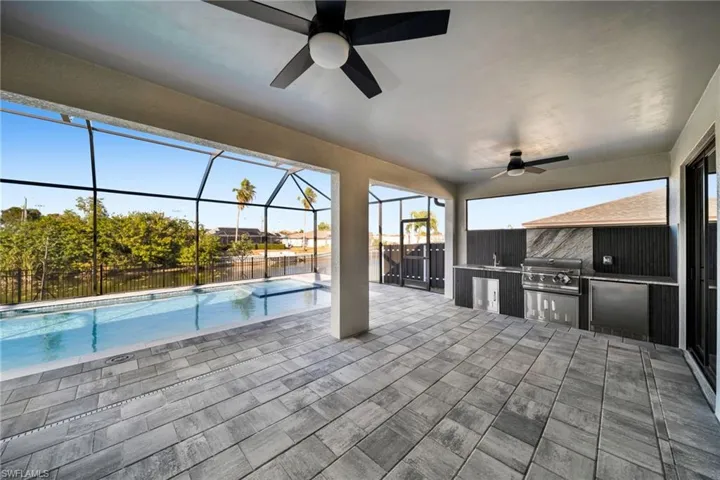 View of patio with a sunroom, exterior kitchen, a lanai, and a ceiling fan