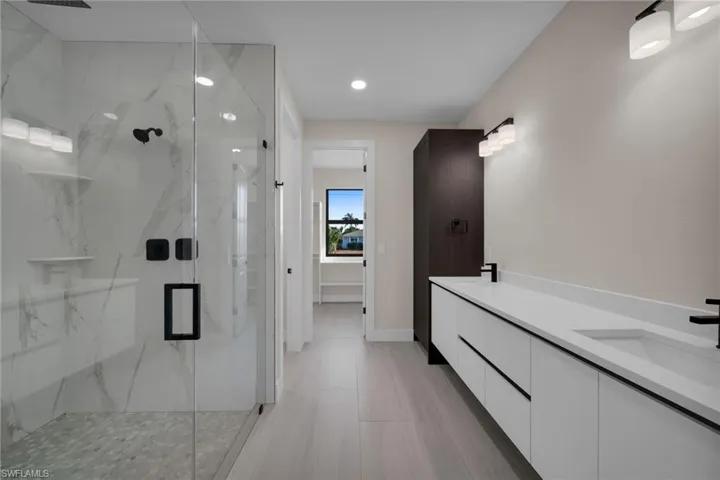 Full bathroom featuring double vanity, a marble finish shower, and recessed lighting