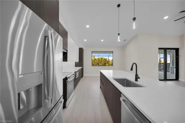 Kitchen with modern cabinets, dark wood finish cabinets, stainless steel appliances, and light stone counters