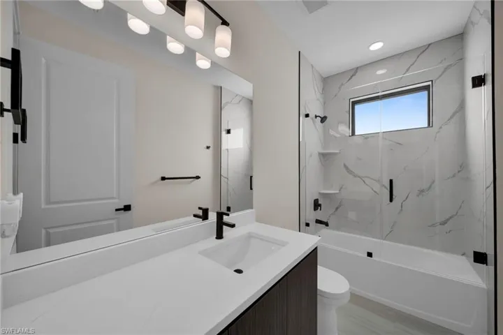Bathroom with bath / shower combo with glass door and vanity