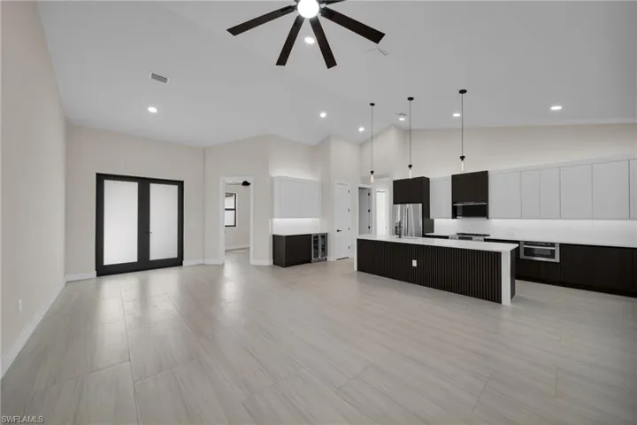 Two tone kitchen with open floor plan, a center island, pendant lighting, ceiling fan, and two tone cabinets