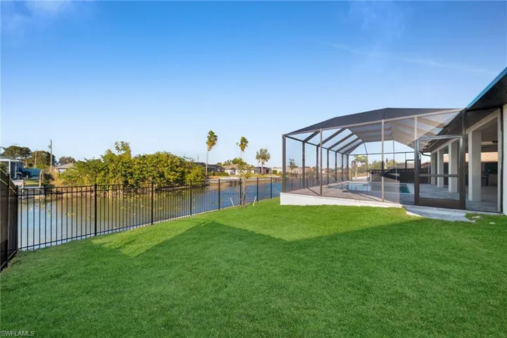 Fenced backyard featuring a lanai, a sunroom, and a water view