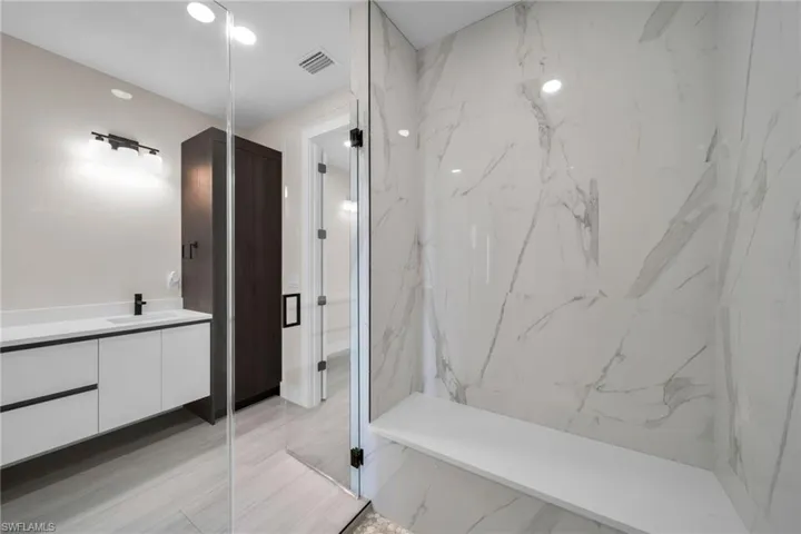 Bathroom with vanity and a marble finish shower