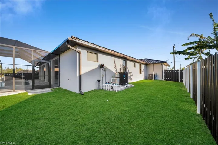 Rear view of property with a lanai, a sunroom, stucco siding, a fenced backyard, and a metal roof