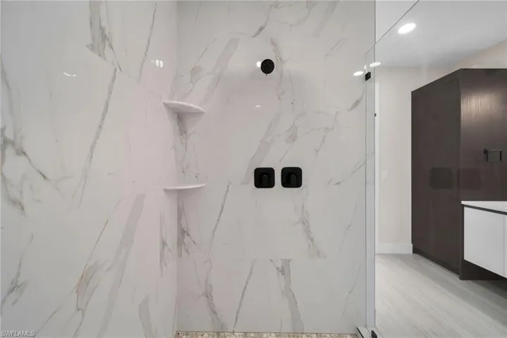 Full bath with a marble finish shower, vanity, and recessed lighting