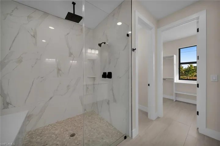 Full bath with a walk in closet and a marble finish shower