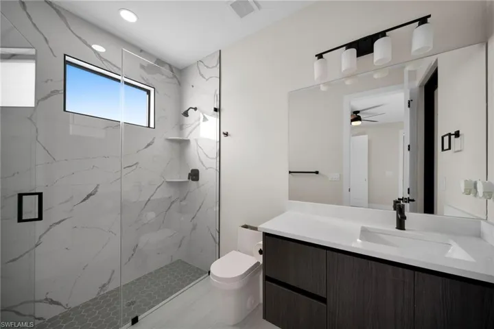 Bathroom featuring a marble finish shower and vanity