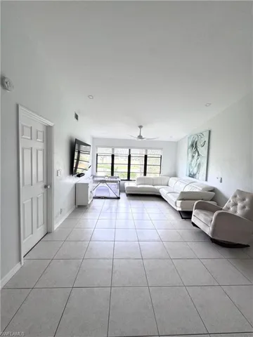 Living room with ceiling fan and light tile patterned floors