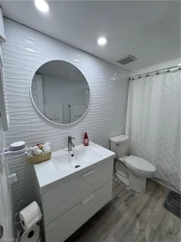 Bathroom with tile walls, vanity, a shower with curtain, wood finished floors, and recessed lighting