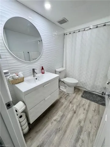 Bathroom featuring vanity, light wood-style flooring, a shower with shower curtain, tile walls, and recessed lighting