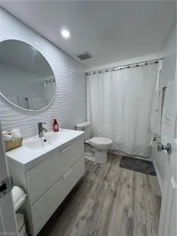 Bathroom featuring vanity, light wood-type flooring, shower / bath combination with curtain, and recessed lighting