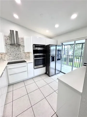 Kitchen featuring white cabinets, modern cabinets, stainless steel appliances, backsplash, and recessed lighting
