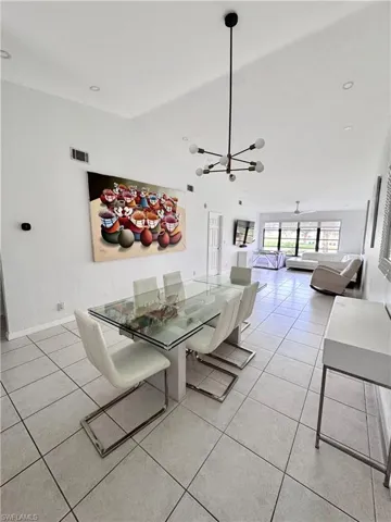 Dining area featuring vaulted ceiling, light tile patterned flooring, and hanging lights