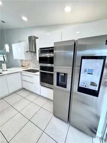 Kitchen featuring white cabinetry, stainless steel appliances, decorative backsplash, pendant lighting, and modern cabinets