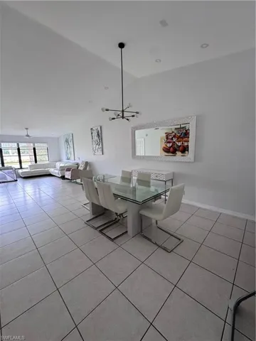 Dining space featuring light tile patterned floors, lofted ceiling, and hanging lights