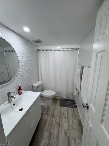 Bathroom with vanity, light wood finished floors, tile walls, and recessed lighting