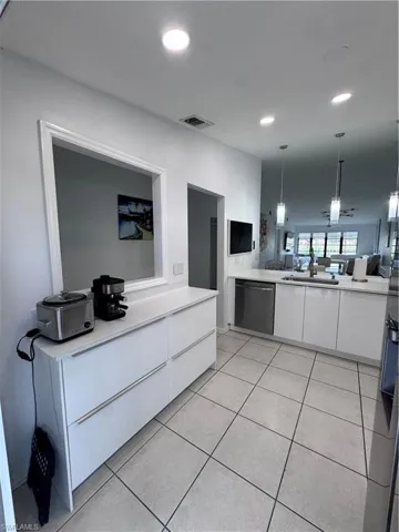 Kitchen with white cabinetry, modern cabinets, hanging light fixtures, open floor plan, and dishwashing machine