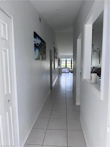 Hallway with light tile patterned floors and a textured wall
