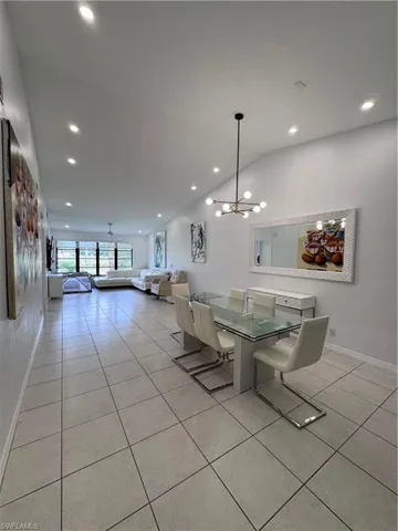 Dining room featuring light tile patterned flooring, vaulted ceiling, and suspended lighting