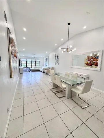 Dining area with light tile patterned floors, a chandelier, and lofted ceiling