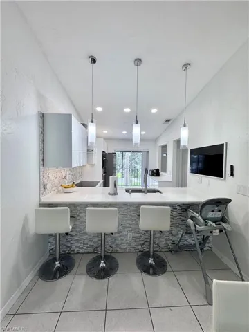 Kitchen featuring a breakfast bar, a peninsula, pendant lighting, and a textured wall
