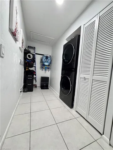 Laundry area with stacked washer / dryer and light tile patterned floors