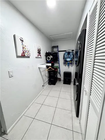 Laundry area featuring stacked washer and clothes dryer and light tile patterned flooring