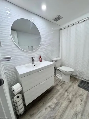 Bathroom with tile walls, vanity, wood finished floors, and a shower with shower curtain