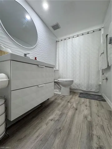 Full bath featuring light wood-style floors, shower / bath combo with shower curtain, and vanity