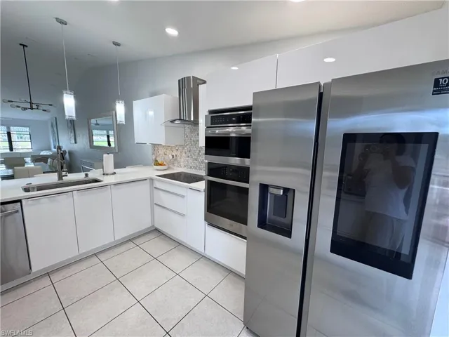 Kitchen featuring stainless steel appliances, white cabinets, open floor plan, tasteful backsplash, and modern cabinets