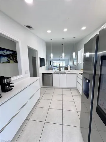 Kitchen featuring white cabinetry, modern cabinets, stainless steel appliances, pendant lighting, and light tile patterned floors