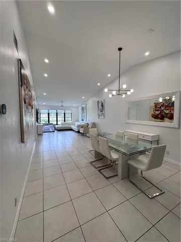 Dining area featuring light tile patterned floors, a chandelier, and vaulted ceiling