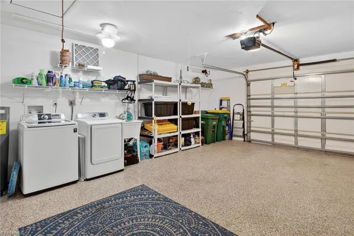 Garage featuring independent washer and dryer, water heater, and a garage door opener