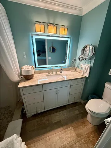 Bathroom with vanity, wood finished floors, a tile shower, and crown molding