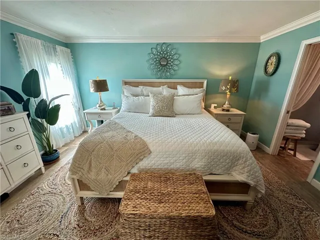 Bedroom with wood finished floors and crown molding