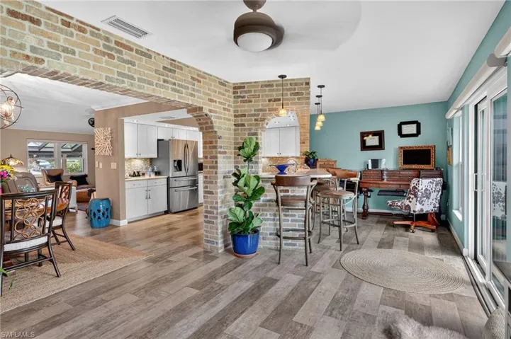 Dining area featuring light wood finished floors, a ceiling fan, arched walkways, and a chandelier