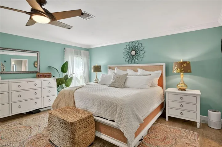 Bedroom featuring wood finished floors, ornamental molding, and a ceiling fan