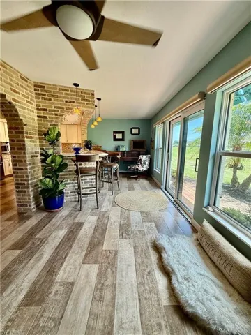 Dining area with wood finished floors, brick wall, ceiling fan, and arched walkways