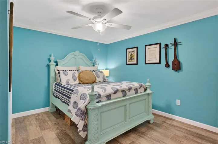 Bedroom featuring ornamental molding, wood finished floors, and a ceiling fan